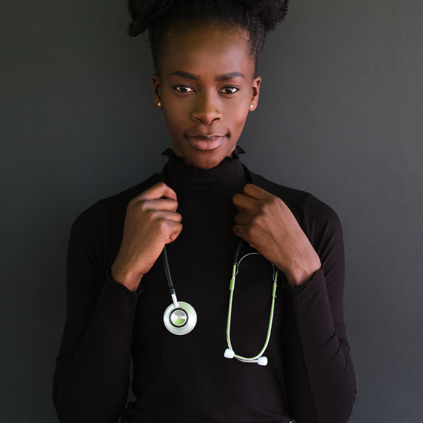 Portrait of young female african doctor with stethoscope in a black background. Studio shot.